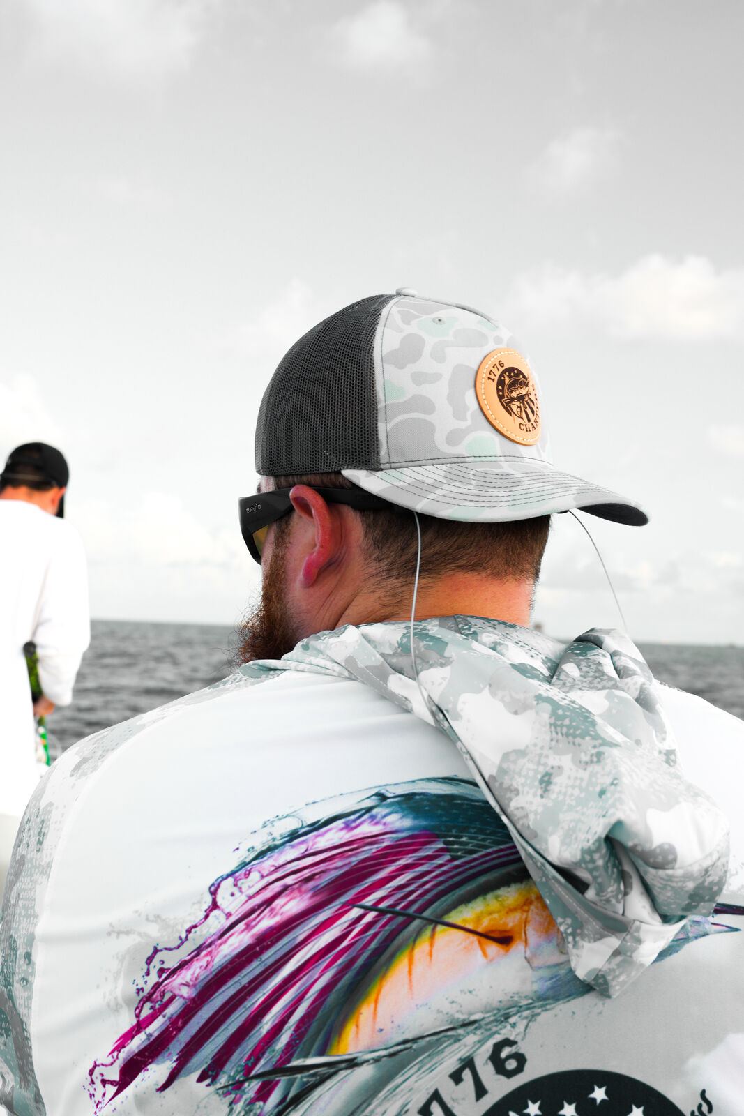 Angler in a 1776 Charters performance shirt working a rod offshore
