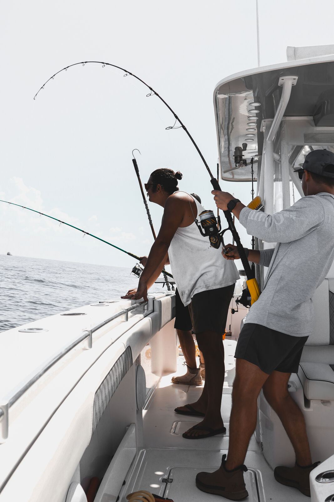 Two anglers hooked up and fighting fish off the stern in the Gulf