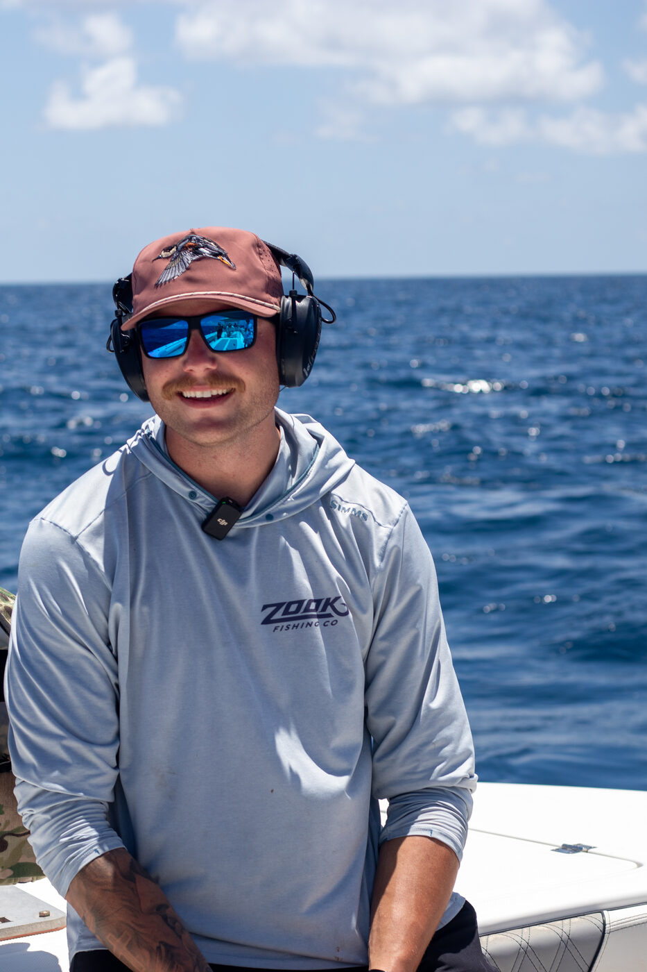 Smiling 1776 Charters crew member in ear protection on the boat offshore