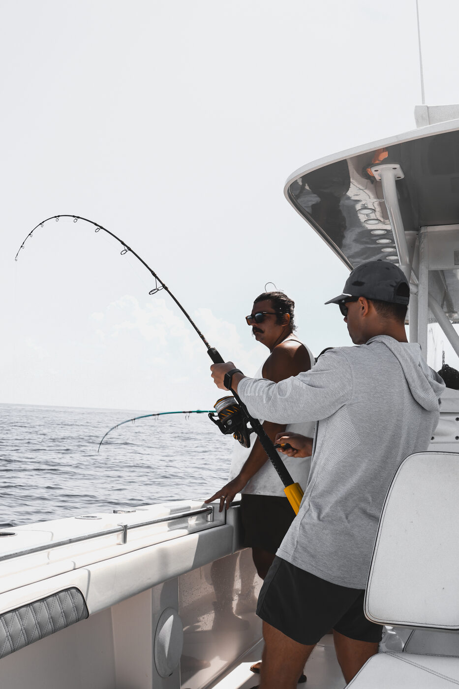 Angler with a deeply bent rod fighting a fish over the rail offshore aboard 1776 Charters