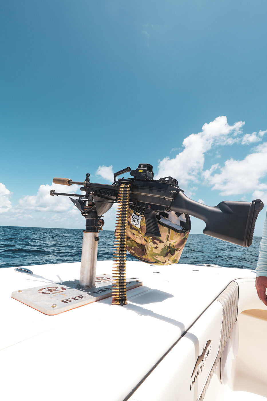Belt-fed machine gun mounted on the bow of the 1776 Charters boat against deep blue Gulf water