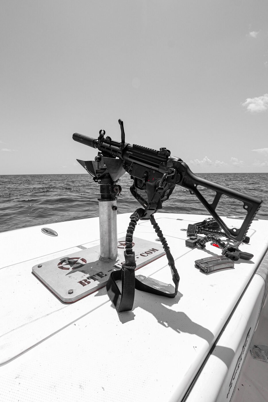 Belt-fed machine gun laid on its deck mount aboard 1776 Charters under a bright sky