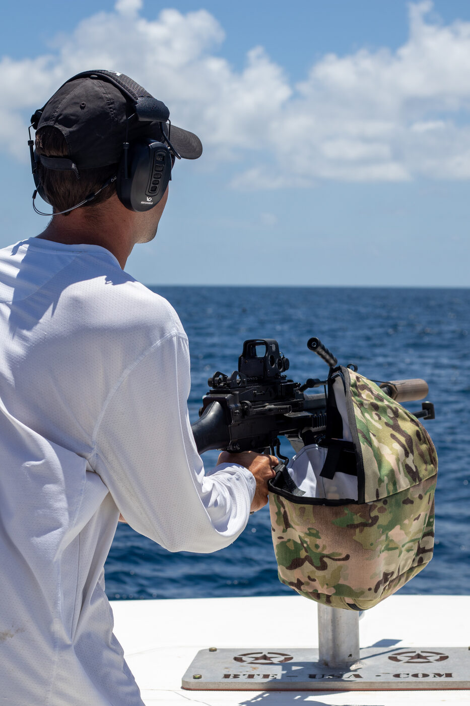 1776 Charters crew member firing the mounted belt-fed machine gun over the open Gulf