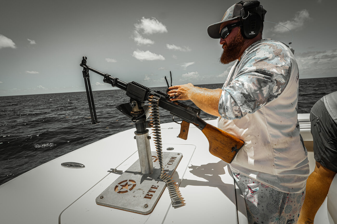 Crew member loading the ammo belt into the mounted machine gun on the bow offshore