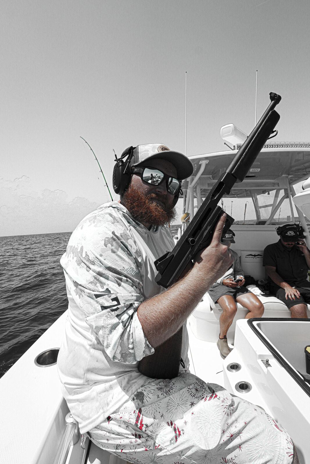Guest holding a submachine gun with ear protection on the deck offshore